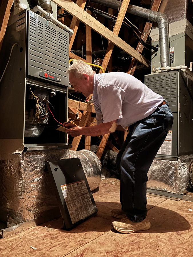 Porter-looking-into-an-ac-air-handler-in-attic
